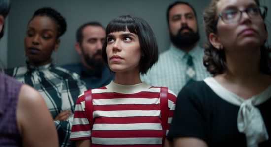 Cena da série Onisciente, da Netflix. A protagonista Nina está num elevador cercada de gente
